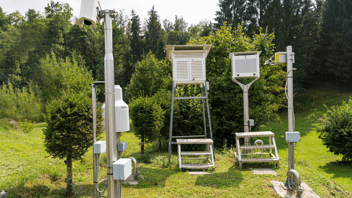 Weather station on grass in green forest 